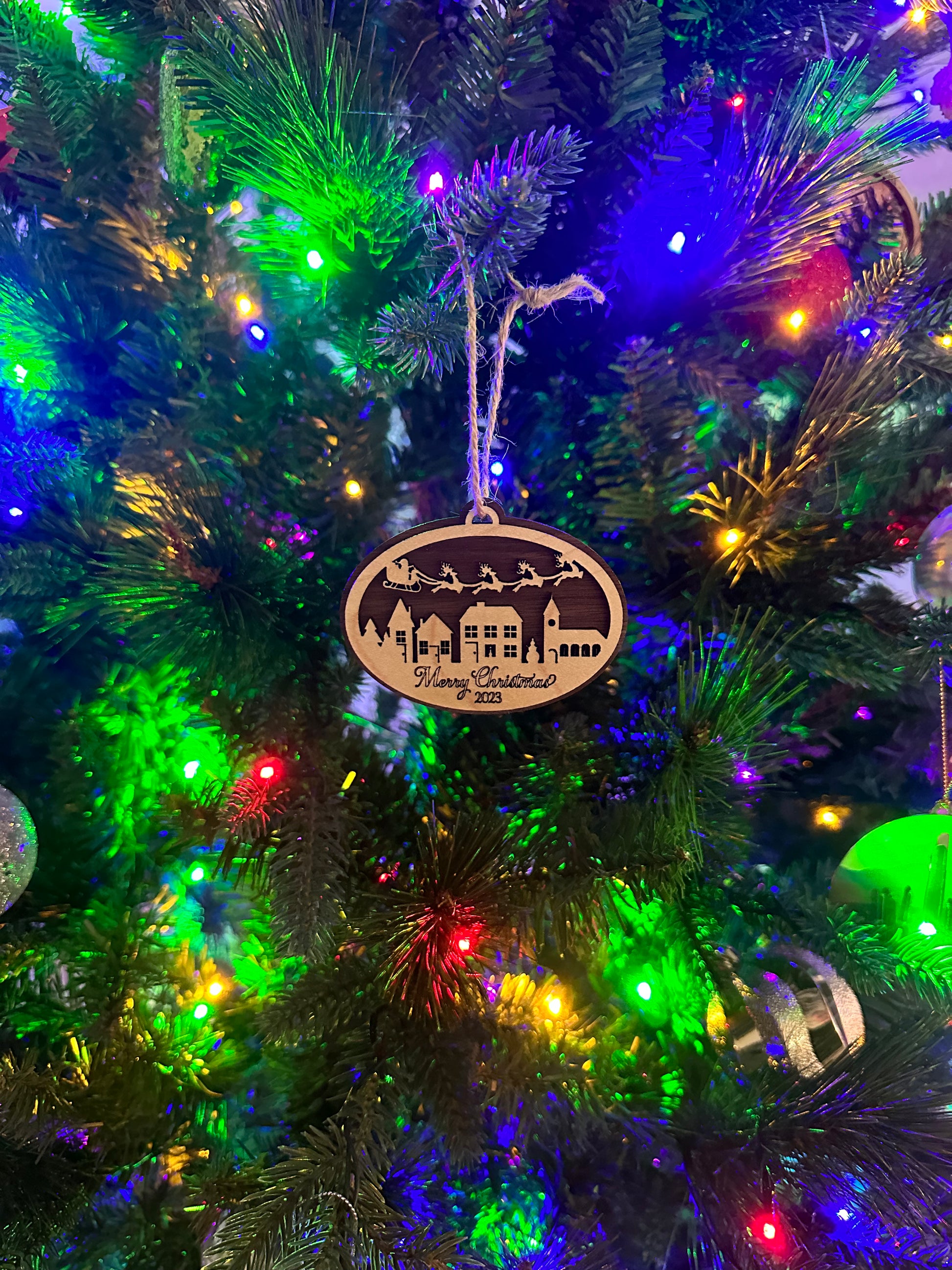 Mark your 2023 Christmas with this chic wooden trinket -- Santa and his sleigh soaring over a village below -- "Merry Christmas 2023" engraved on the bottom. This ornament make a perfect gift or a great way to commemorate your 2023 Christmas.