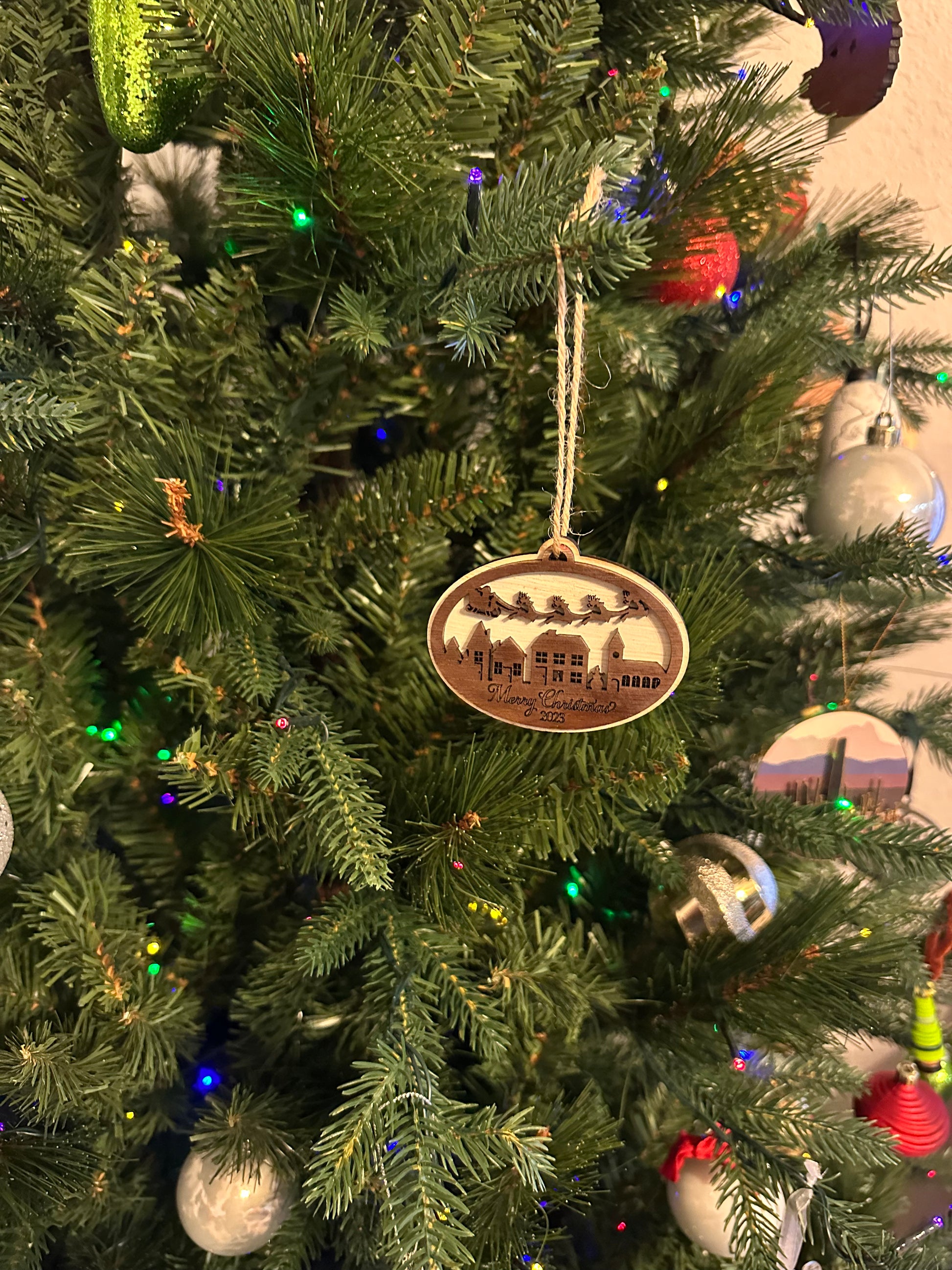 Mark your 2023 Christmas with this chic wooden trinket -- Santa and his sleigh soaring over a village below -- "Merry Christmas 2023" engraved on the bottom. This ornament make a perfect gift or a great way to commemorate your 2023 Christmas.